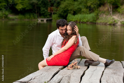 Couple of people in love sit on the bridge © Elena Oleshko