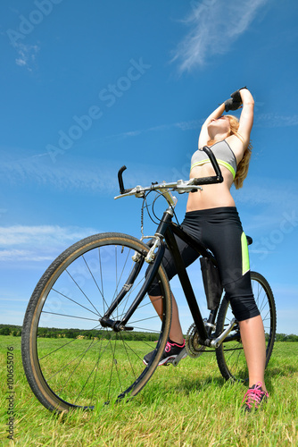 Girl with bicycle on meadow