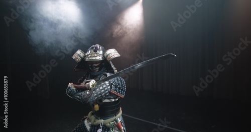 Japanese samurai in the historical suit threatens with a sword , posing for the camera, slow motion photo