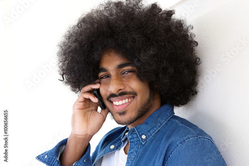 Smiling young man with afro using cellphone