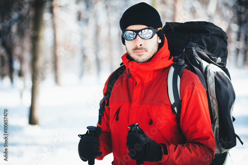 Man hiking at winter mountain/Portrait of a man hiker. He is trekking in snow forest at winter mountain. Healthy lifestyle winter adventure