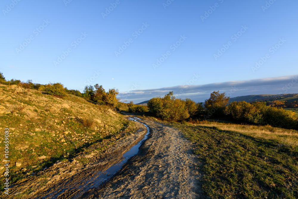 Rural road in autumn landscape. Mountain rural road with water a