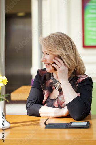 Mature beautiful woman is calling on a cell phone while sitting