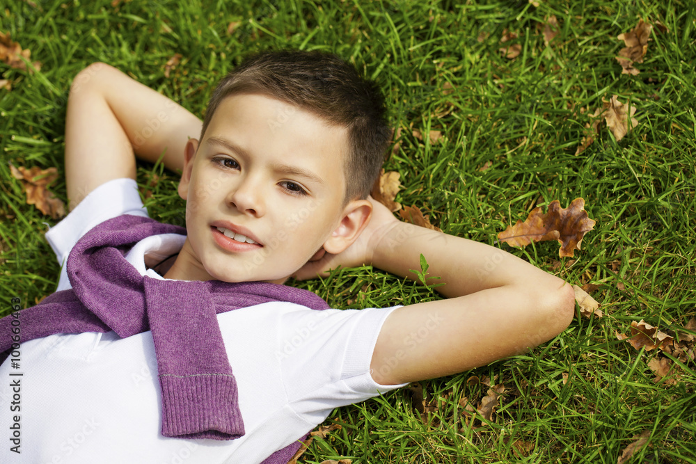 Brunette little boy laying on the grass in the park Brunette little boy laying on the grass in the park