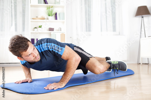 Fit Man Planking on Mat While Lifting One Leg
