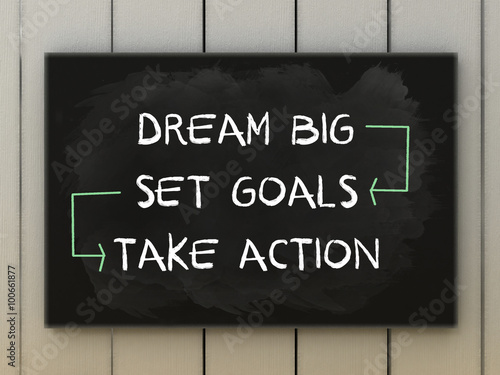 Dream big, set goals, take action on blackboard written with chalk.