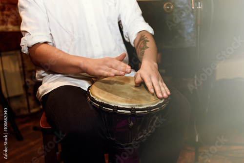 Fototapeta stylish percussionist playing on leather drum on a concert, hand