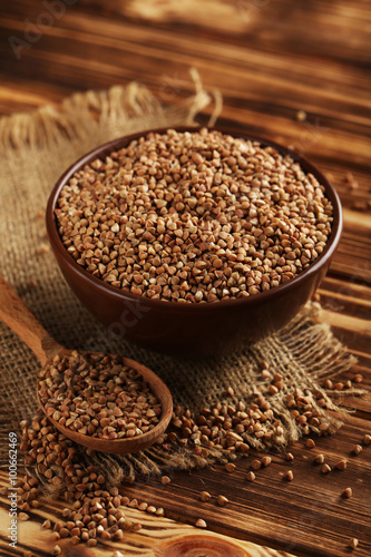 Buckwheat seeds in wooden spoon on a brown wooden table