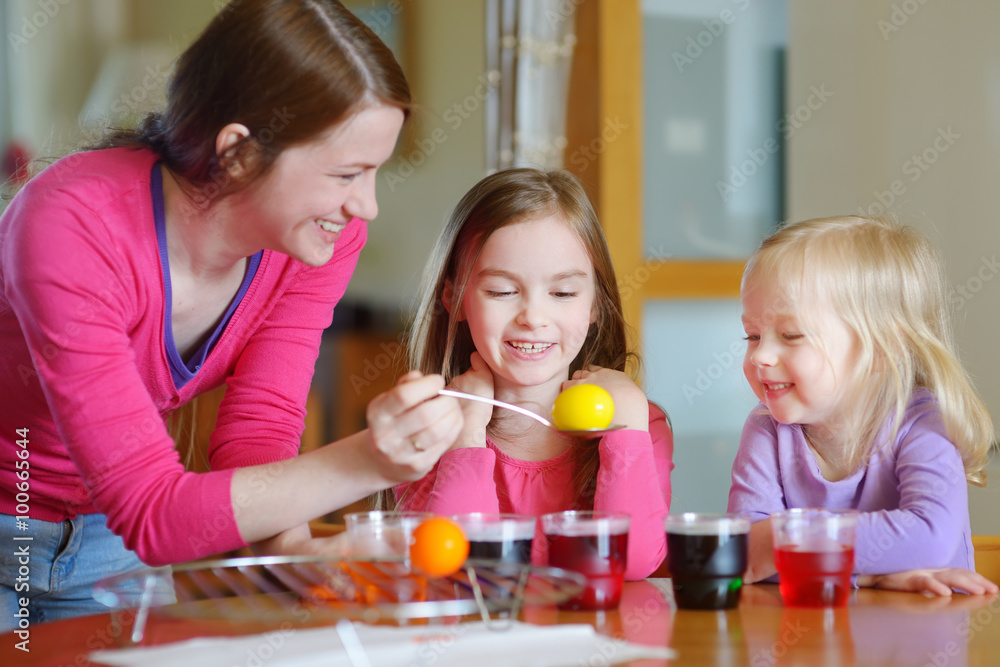 Young mother and her two daughters painting Easter eggs Young mother and her two daughters painting Easter eggs