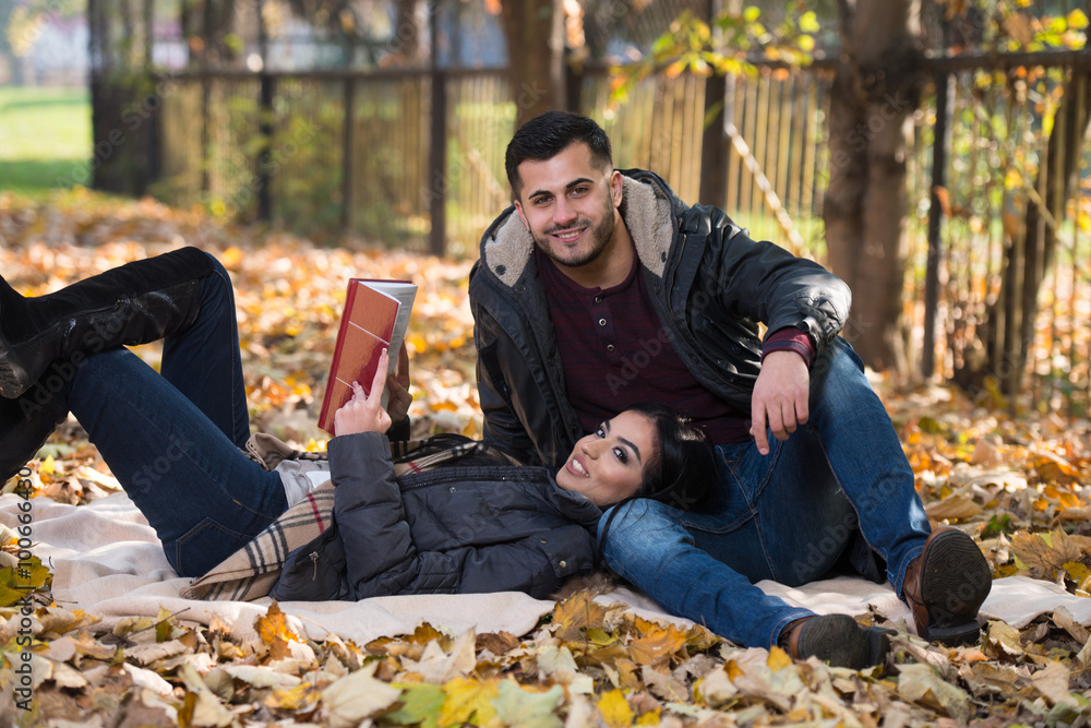 Couple Enjoying Book Reading In Autumn Park