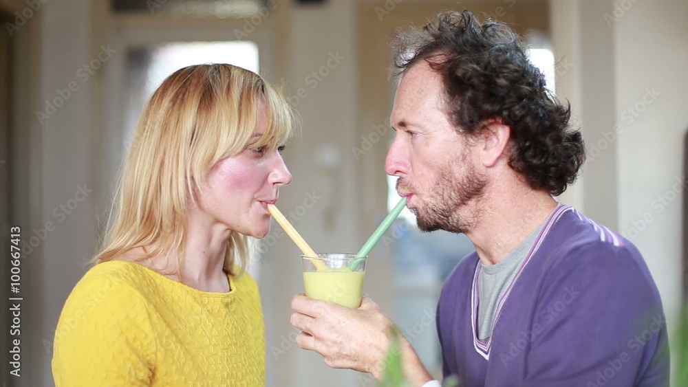 Couple drinking smoothie from same drinking glass Couple drinking smoothie from same drinking glass