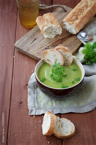 Cream soup of green peas on a wooden background