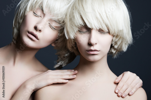 Portrait of two beautiful girls twins with closed eyes in studio
