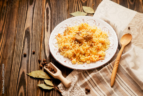 
national cuisine , stewed rice with meat , which is called pilaf with bay leaf and pepper on a wooden background 