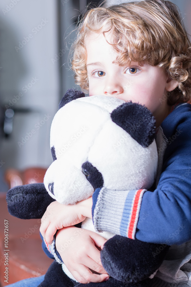 Close-up of lovely blond boy with curly hair hugging panda toy Close-up of lovely blond boy with curly hair hugging panda toy