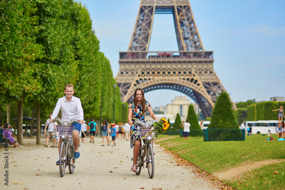 Obraz premium couple riding bicycles near the Eiffel tower in Paris