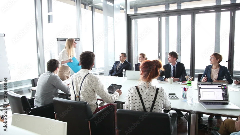 Business people sitting at table while female colleague giving presentation Business people sitting at table while female colleague giving presentation
