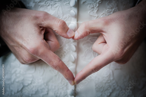 Ein mit den Fingern geformtes Herz hinter dem Rücken der Braut