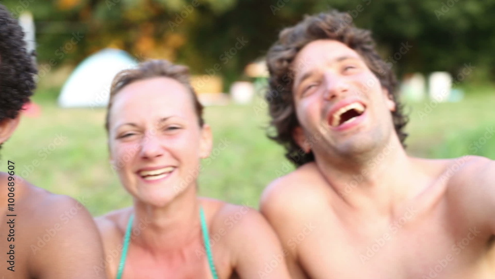 Portrait of group of friends sitting in nature, laughing at camera Portrait of group of friends sitting in nature, laughing at camera