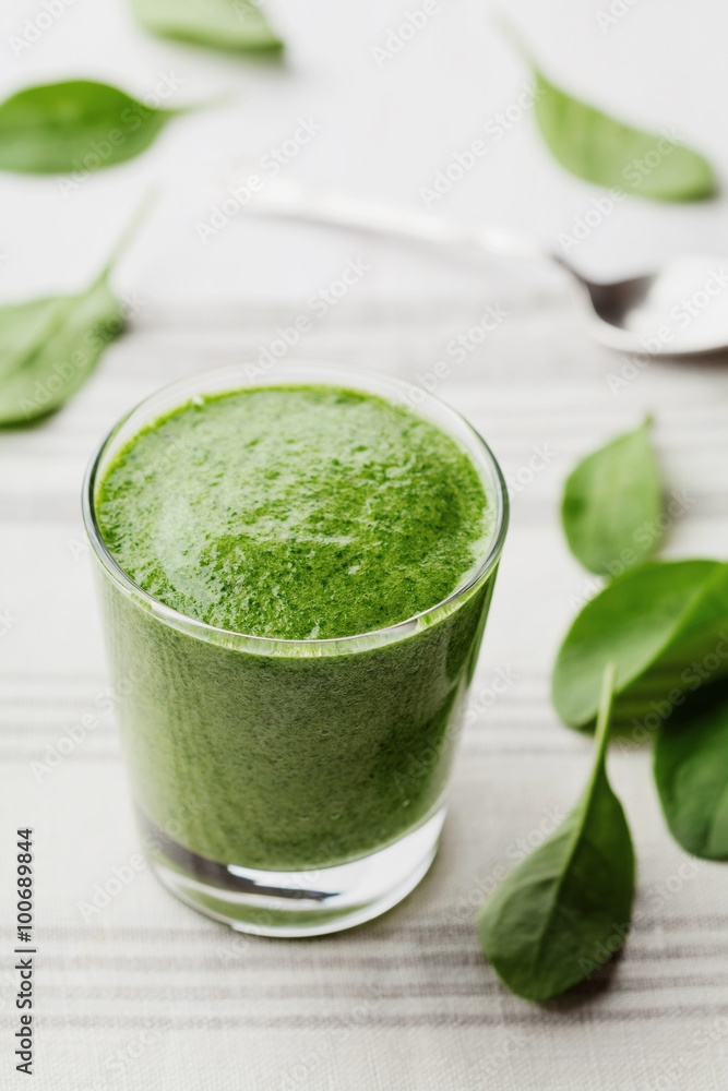 Green spinach smoothie in glass on white table, detox and diet food for breakfast Green spinach smoothie in glass on white table, detox and diet food for breakfast