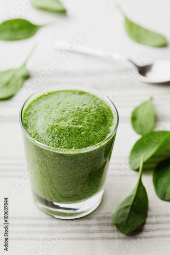 Green spinach smoothie in glass on white table, detox and diet food for breakfast