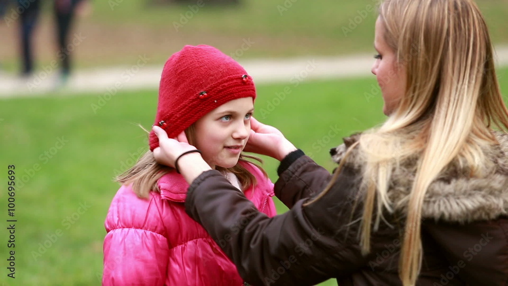 Mom putting cap on daughter's head and kissing her in forehead Mom putting cap on daughter's head and kissing her in forehead