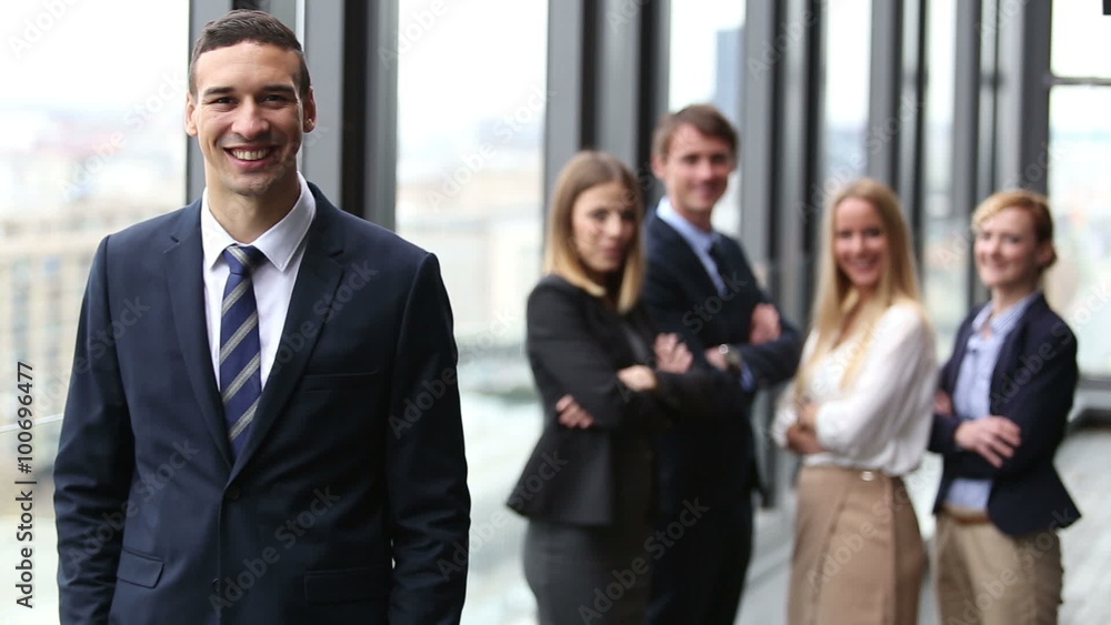 Portrait of young director smiling, colleagues in background Portrait of young director smiling, colleagues in background