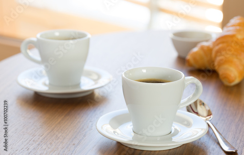 Two cups of coffee with croissants.