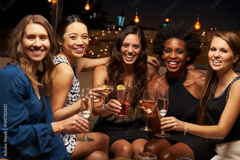 Portrait Of Female Friends Enjoying Night Out At Rooftop Bar