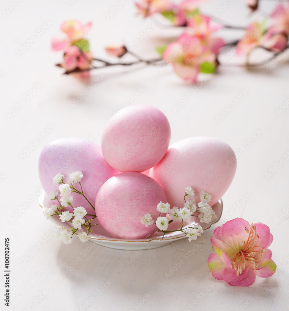 Plate with pink Easter eggs and artificial flowers on wooden table. Focus on the Easter eggs Plate with pink Easter eggs and artificial flowers on wooden table. Focus on the Easter eggs