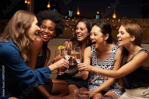 Group Of Female Friends Enjoying Night Out At Rooftop Bar photo