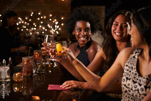 Female Friends Enjoying Night Out At Cocktail Bar