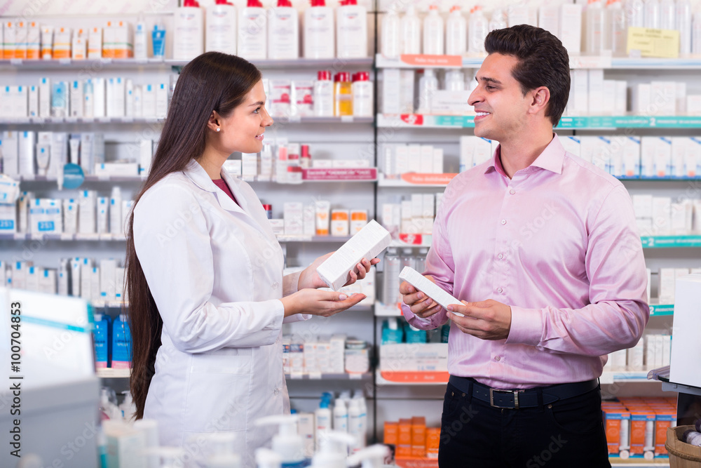 Pharmacist and customer in drugstore .