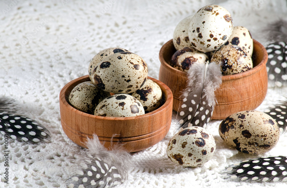Quail eggs in two wooden bowls and feathers Quail eggs in two wooden bowls and feathers