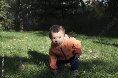 Cute Chinese baby boy studying a fountain blow hole in grass