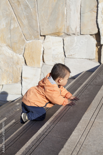 Cute Chinese baby boy crawling on stairs outdoors