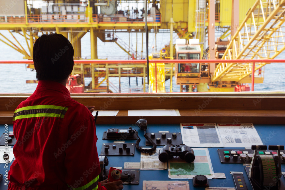 Obraz premium A helmsman on the bridge of a supply vessel nearby an offshore oil-rig