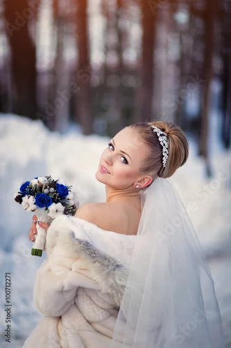 Obraz bride posing in the winter forest in a fur coat. Wedding photo