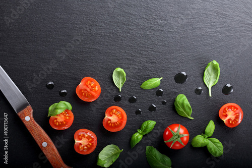 Cherry tomatoes with basil on stone background and space for tex