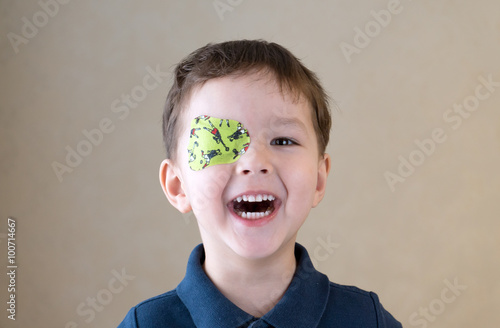 Fototapeta Little boy with okluder on the eye.