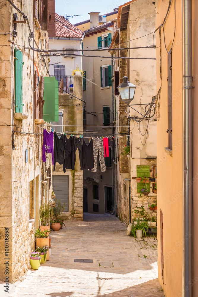 Fototapeta premium Wąska ulica z wiszącymi ubraniami - Rovinj, Chorwacja
