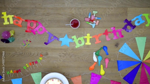 Happy birthday background them, seen from above - top view - with garlands banners candles and a birthday cake on a wooden background  photo