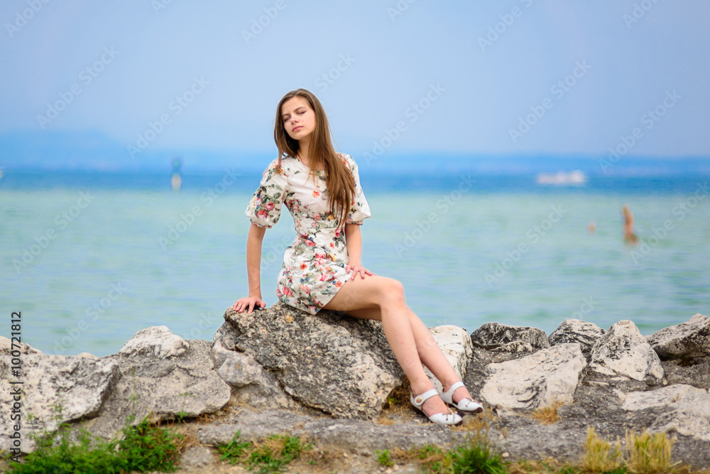 Beautiful woman sitting on rock over sea Beautiful woman sitting on rock over sea