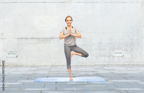 woman making yoga in tree pose on mat