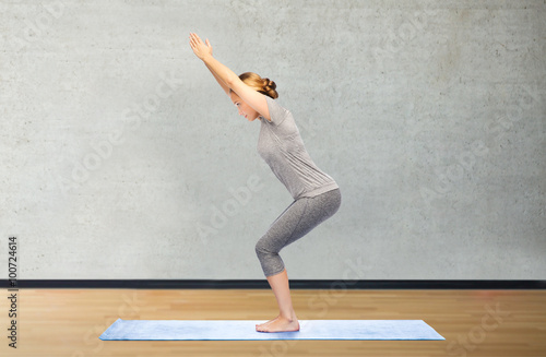 woman making yoga in chair pose on mat