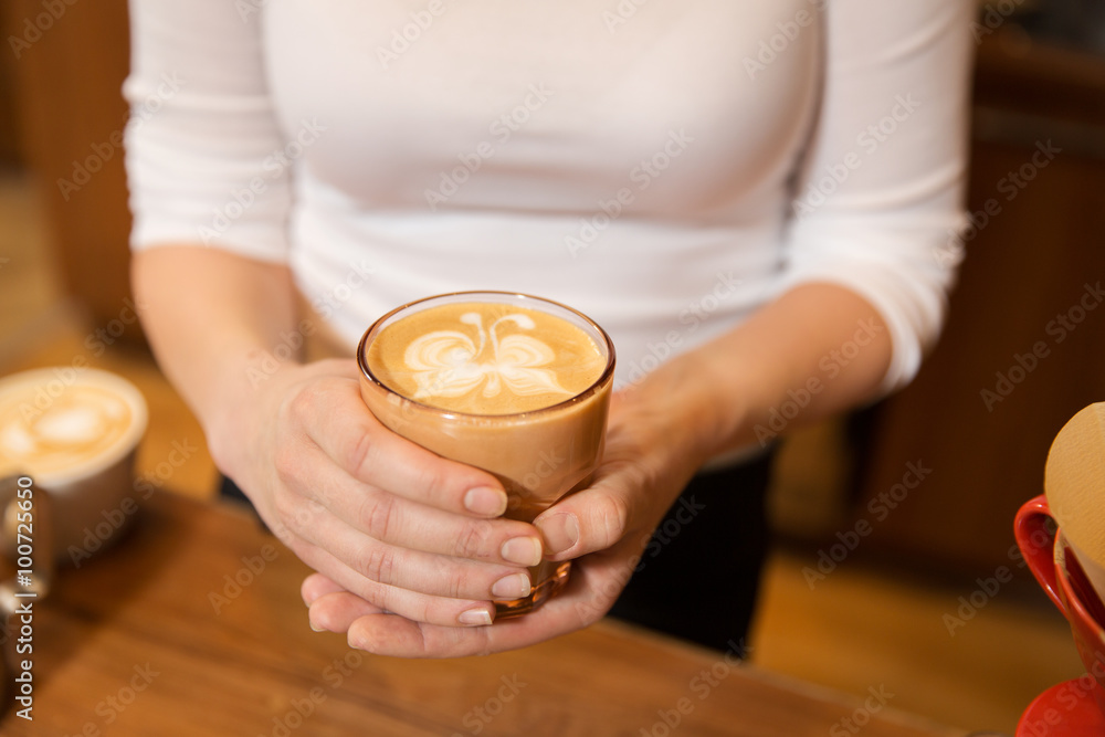 close up of hands with latte art in coffee cup close up of hands with latte art in coffee cup