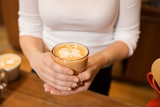 close up of hands with latte art in coffee cup