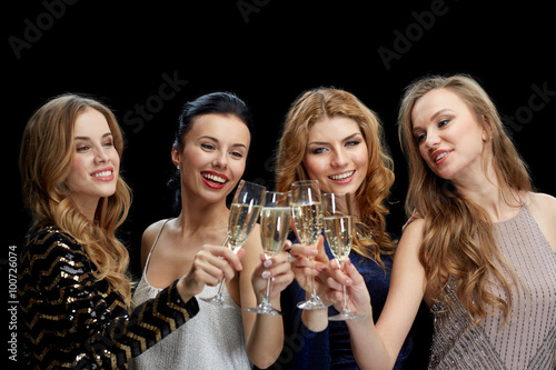 happy women clinking champagne glasses over black
