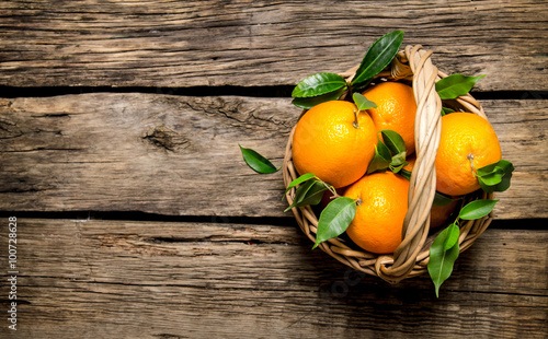 Fresh oranges in the basket with leaves.