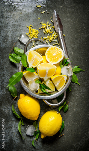 Fresh lemons in a saucepan with leaves and zest.